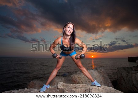 The girl with a sports figure does exercises with dumbbells