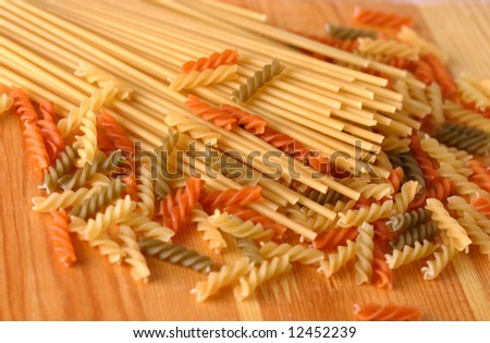 Raw color pasta background on yellow wooden cook-table