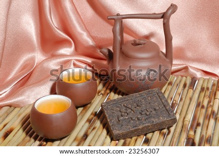 Chinese teapot and cups with black pu-erh tea from yunnan province in China. Leaves undergoes double fermentation and compressed into bricks. Healthy drink.
