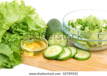 Fresh tasty lettuce, vegetable oil and cucumber on a cutting board on white background