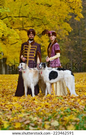 Nesvizh, Belarus - October 12: Couple in traditional medieval costumes with two borzoi dogs represents everyday life of Grand Duchy of Lithuania. In Nesvizh, Belarus on October 12, 2013.