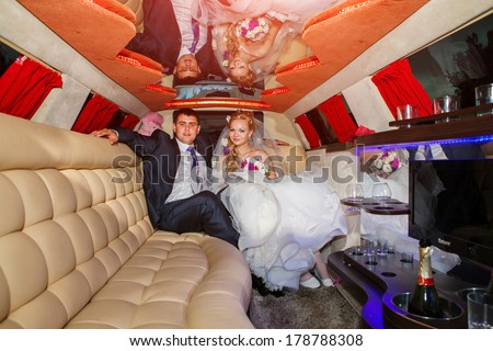 Happy young couple sitting in limousine on wedding day.