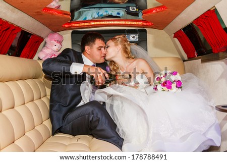 Bride and groom kissing in limousine on wedding-day.