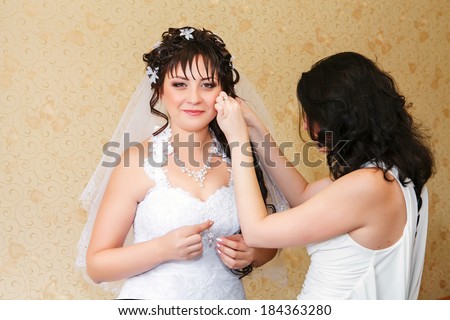 Young beautiful bride applying wedding make-up by make-up artists