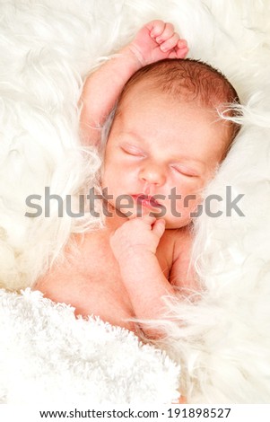 Newborn baby boy asleep on a fur blanket.
