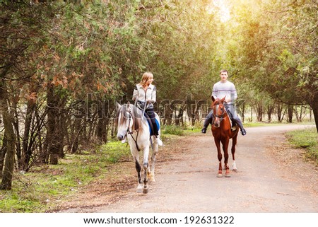 Young couple riding a brown horse at countryside at summer