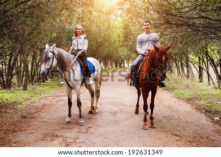 Young couple riding a brown horse at countryside at summer