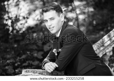 Close-up portrait of a good looking beautiful young man in costume outdoors. Black-white photo.