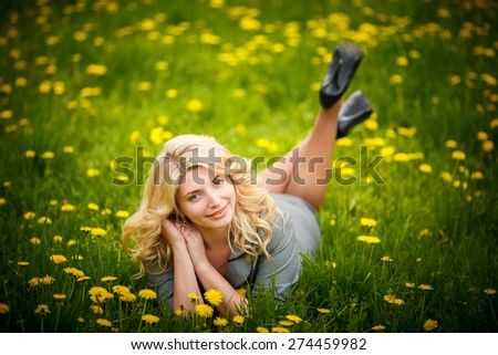 pretty woman lying down on dandelions field, happy cheerful girl resting on dandelions meadow, relaxation outdoor in springtime, vacation