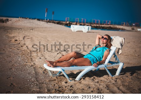 Woman sits on chair in sea sand sun