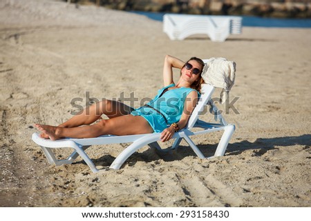 Woman sits on chair in sea sand sun