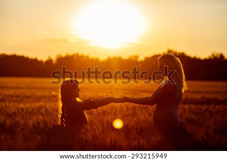 Young happy beautiful mother and her daughter . Happy family jumping together in a circle having fun and expressing emotions of joy, freedom, success. Silhouettes on sunny sky