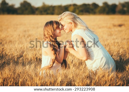 Young happy beautiful mother and her daughter . Happy family. Expressing emotions of joy, freedom, success. Silhouettes on sunny sky