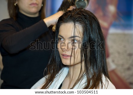 Pretty lady sitting while hairdresser dries her hair