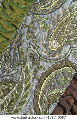 textile with quilting detail closeup green and brown satin with paisley print on diagonal