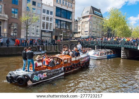 AMSTERDAM - APRIL 27: Boat party through Amsterdam canals on fine weather during King\'s Day on April 27,2015, the Netherlands. Kings Day is biggest festival celebrating the birth of Dutch royalty.