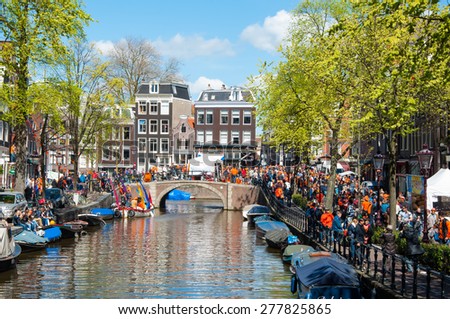 AMSTERDAM-APRIL 27: Crowd of people go along Amsterdam street to celebrate King\'s Day on April 27,2015. King\'s Day is the largest open-air festivity in Amsterdam, the Netherlands.