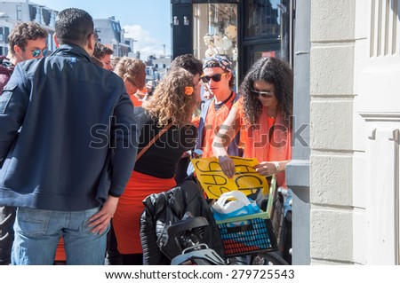 AMSTERDAM-APRIL 27: Unidentified woman sells laughing gas to young men during King\'s Day on April 27,2015 in Amsterdam, the Netherlands.