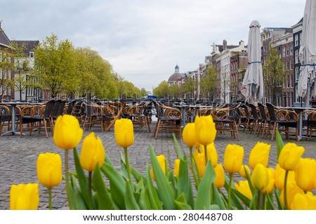 Amsterdam cityscape with tulips and outside cafe on the background, the Netherlands.