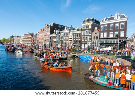 AMSTERDAM-APRIL 27: People in orange on boats participate in celebrating King\'s Day through Singel canal on April 27,2015 the Netherlands. King\'s Day is the largest open-air festivity in Amsterdam.