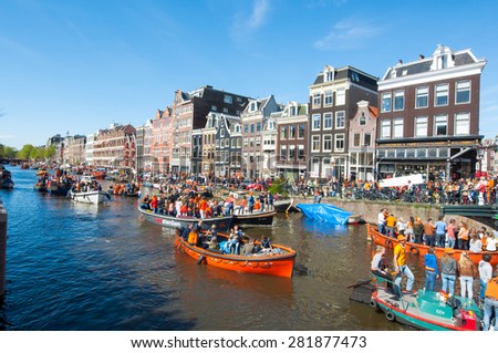 AMSTERDAM-APRIL 27: Local people and tourists on the boats participate in celebrating King\'s Day through Singel canal on April 27,2015. King\'s Day is the largest open-air festivity in Amsterdam.