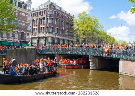 AMSTERDAM-APRIL 27:  King\'s Day (Koningsdag) boating on the Singel canal,  crowd of people watch the festival on the bridge on April 27, 2015. King\'s Day is held on 27 April every year.