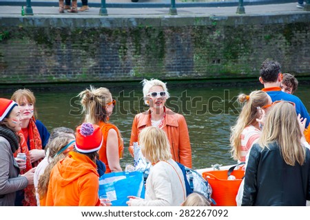 AMSTERDAM-APRIL 27: Happy locals and tourists in orange have fun on a boat during King\'s Day on April 27,2015, the Netherlands. King\'s Day is the largest open-air festivity in Amsterdam.