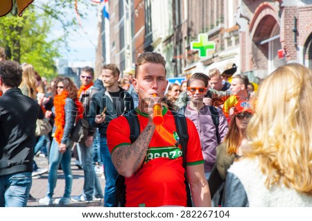 AMSTERDAM-APRIL 27: Undefined person play the pipe, crowd of People have fun on Amsterdam street During King\'s Day on April 27,2015. King\'s Day is the largest open-air festivity in Amsterdam.