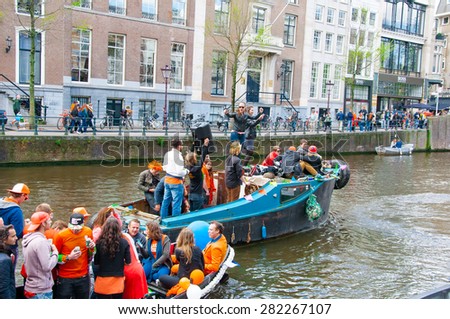 AMSTERDAM,NETHERLANDS-APRIL 27: Cheerful people in orange have fun on a boat during King\'s Day on April 27,2015. King\'s Day is the largest open-air festivity in Amsterdam.