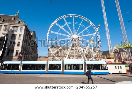 AMSTERDAM-APRIL 27: Big wheel on Dam Square on the eve of King\'s Day, Madam Tussaud\'s museum on the left-hand side on April 27,2015.  King\'s Day is the largest open-air festivity in Amsterdam.