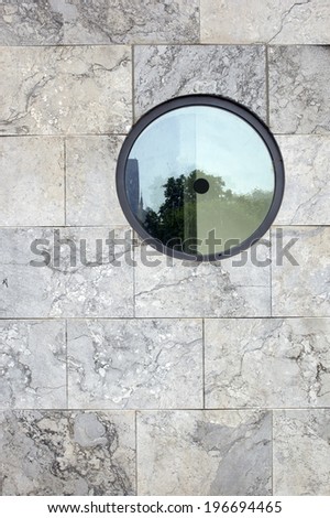 The photograph of a granite wall with a round window / Wall with round window