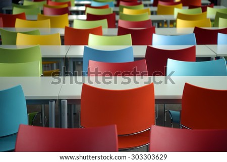 Empty rows of seats with tables and colorful chairs in the space of an educational institution or school / Rows of seats with colorful chairs