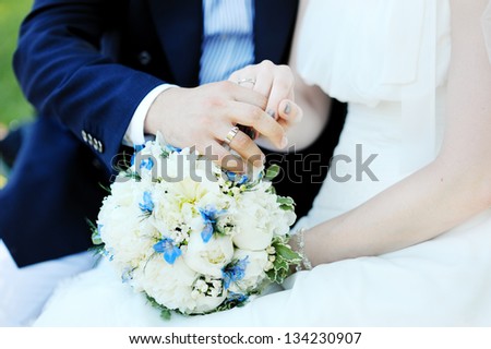 hands of the bride and the groom with bouquet and wedding rings