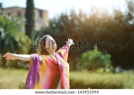 young beautiful woman relaxing with open arms and face turned to sun