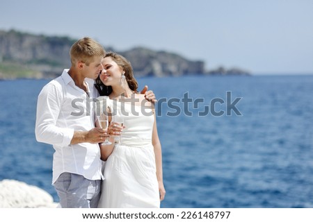 couple making a toast by the sea after their wedding