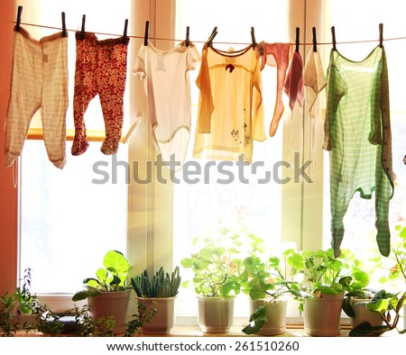 Baby laundry hanging on a clothesline with sun rising on a background