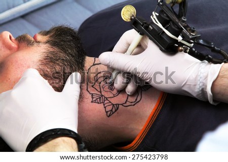 tattooer showing process of making a tattoo. Tattoo design in the form of rose flower