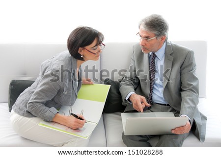 Businessman and businesswoman sitting on couch and working together