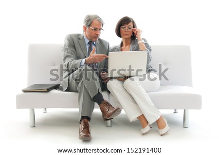 Two business people sitting and working together on a white sofa