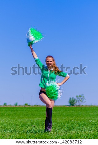 Cheerleader girls dances over the grass