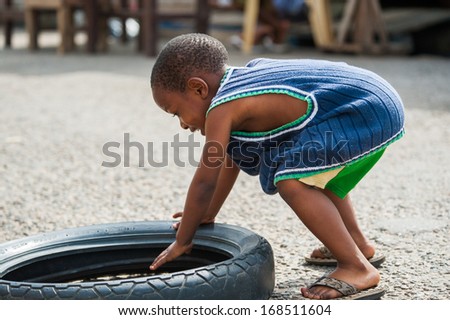 GHANA - MARCH 2, 2012: Unidentified Ghanaian boy plays with a car tire on the street in Ghana, on March 2nd, 2012. People in Ghana suffer from poverty due to the slow development of the country