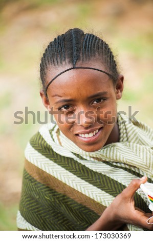 AKSUM, ETHIOPIA - SEP 24, 2011:Unidentified Ethiopian cute little girl in green tissue near the stone wall in Ethiopia, Sep.24, 2011. People in Ethiopia suffer of poverty due to the unstable situation