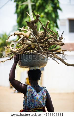 KARA, TOGO - MARCH 11, 2012: Unidentified Togolese woman carries a bucket of wood on her head in Togo, Mar 11, 2012. People in Togo suffer of poverty due to unstable economical situation