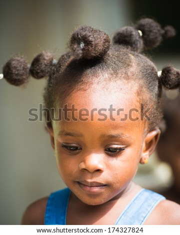 LIBREVILLE, GABON - MAR 6, 2013: Unidentified Gabonese little girl with a funny haircut smiles in Gabon, Mar 6, 2013. People of Gabon suffer of poverty due to the unstable economical situation