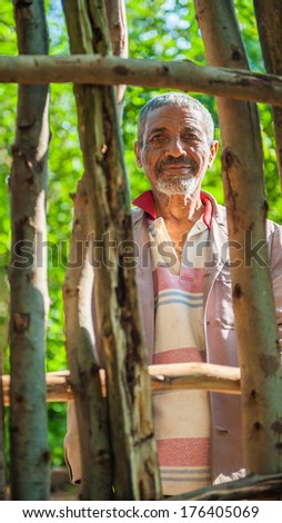 OMO, ETHIOPIA - SEPTEMBER 19, 2011: Unidentified Ethiopian old man stays behind the wooden fence. People in Ethiopia suffer of poverty due to the unstable situation