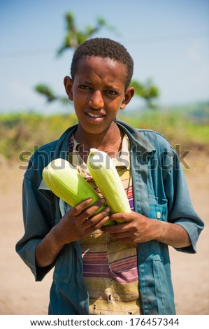 AKSUM, ETHIOPIA - SEPTEMBER 22, 2011: Unidentified Ethiopian boy sells maize in the desert. People in Ethiopia suffer of poverty due to the unstable situation