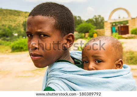 AKSUM, ETHIOPIA - SEPTEMBER 24, 2011: Unidentified Ethiopian boy carries his little brother on his back. People in Ethiopia suffer of poverty due to the unstable situation