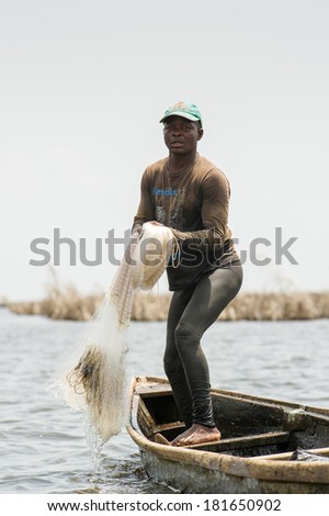 PORTO-NOVO, BENIN - MAR 9, 2012: Unidentified Beninese father throws the fish net into the water to catch the fish. People of Benin suffer of poverty due to the difficult economic situation.