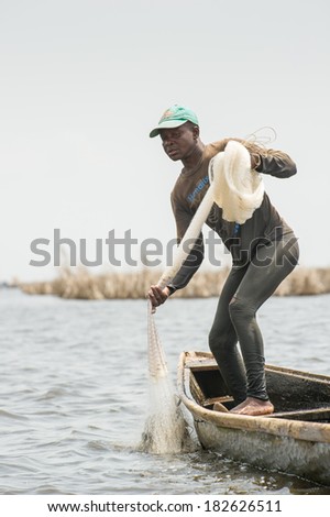 PORTO-NOVO, BENIN - MAR 9, 2012: Unidentified Beninese father throws the fish net into the water to catch the fish. People of Benin suffer of poverty due to the difficult economic situation.