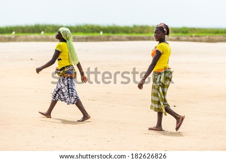 PORTO-NOVO, BENIN - MAR 9, 2012: Unidentified Beninese two women walks over the coast. People of Benin suffer of poverty due to the difficult economic situation.